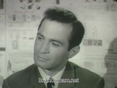 The still features a man in a suit, seated and appearing thoughtful. He is looking slightly to his right, with a neutral expression. The background consists of various newspaper images or print, suggesting a news or media context. The overall tone is serious, typical of promotional material from a television network in the early 1960s.