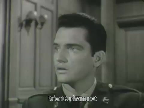 The still from the 'ABC Fall 1963 season promos' features a young man in a military uniform, displaying a look of concern or contemplation. The setting appears to be a wood-paneled room, suggesting a formal or serious atmosphere. His expression conveys intensity, indicating he might be in a pivotal moment related to the storyline.