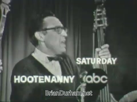 The still features a male performer with glasses, passionately singing or speaking into a microphone while holding a bass instrument. The text overlaid includes 'HOOTENANNY' in bold letters, indicating the show's title, along with 'SATURDAY' and the ABC logo, suggesting it’s a promotional clip for the ABC television network's fall 1963 season lineup. The background appears to be a performance stage with dramatic curtains.