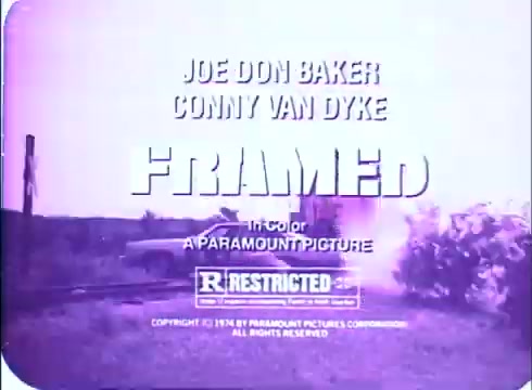 The still from the trailer of 'Framed' features a text overlay displaying the title and key actors, Joe Don Baker and Conny Van Dyke. The aesthetic is characteristic of a vintage 16mm print, with a pinkish hue typical of the era. It is labeled as a Paramount Picture, marked 'R Restricted' and includes a copyright notice from 1974. The background appears to show a scene with a vehicle and possibly an explosion, suggesting an action-oriented context.
