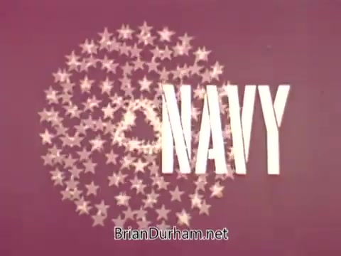 The still features the word 'NAVY' prominently displayed in bold, capital letters, surrounded by a circular arrangement of stars. The background is a soft gradient of colors, likely emphasizing a patriotic theme. The overall design suggests a promotional or recruiting message, typical of public service announcements aimed at attracting interest in U.S. Navy aviation careers.
