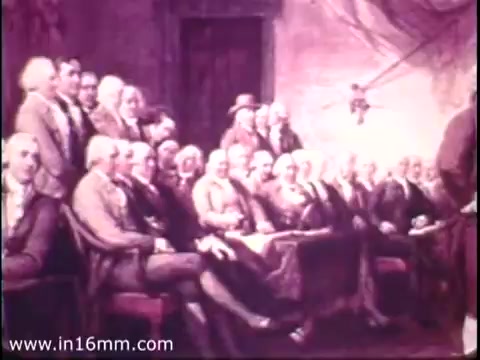 The still depicts a historical gathering, likely related to the founding of the United States, featuring a large group of men seated in a formal setting. They appear engaged in a discussion or debate. The atmosphere suggests a significant moment in history, reflecting the themes of civic engagement and youth participation central to the Bicentennial Youth Debates (BYD) initiative from 1975. This national program aimed to encourage young people to explore critical issues through debate, fostering skills in public speaking and critical thinking.