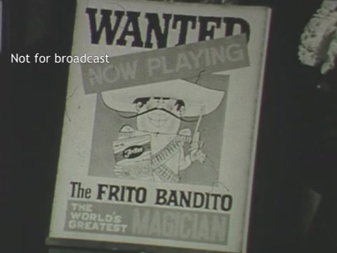 The still features a vintage poster advertising 'The Frito Bandito,' depicted as a cartoonish character wearing a sombrero and mustache. It declares 'WANTED' at the top and 'NOW PLAYING' beneath, along with the tagline 'THE WORLD'S GREATEST MAGICIAN.' The design emphasizes a playful and humorous tone, typical of mid-20th-century advertisements.