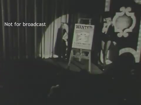 The still features a stage with a spotlight illuminating a 'WANTED' poster, possibly depicting the Frito Bandito character. The background includes draped curtains, suggesting a theatrical or performance setting. The text 'Not for broadcast' indicates this is likely a behind-the-scenes or archival image related to the advertisement featuring Mel Blanc's voiceover.