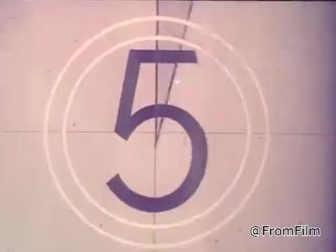 The still features a vintage 16mm film countdown to the number five, set against a simplistic background. It's likely part of a 1970s advertisement for Nestlé semi-sweet chocolate chips, promoting their use in making Toll House cookies. The voiceover emphasizes the importance of fresh, home-baked cookies and highlights the special role of Nestlé’s chocolate morsels in achieving that classic taste. The overall aesthetic reflects the era's advertising style, capturing the warm, homey appeal of baking.