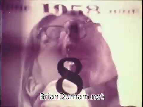 The still from the 1971 Jell-O Pudding in a can commercial features a person drinking from a can, possibly highlighting the convenience of the product. The background includes bold text with the year '1958' and a prominent number '8.' The visual style reflects the era's aesthetics, showcasing the product in a playful and engaging manner.