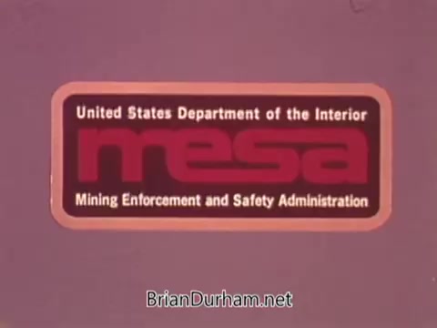 The still features a logo for the Mining Enforcement and Safety Administration (MESA), under the United States Department of the Interior. The logo is prominently displayed with 'MESA' in bold red letters, emphasizing its focus on mining safety and enforcement. The background is a simple color, likely to enhance the visibility of the text and logo, creating a clear and professional presentation related to mining safety initiatives.