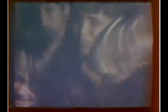 The still depicts a group of children, likely waiting to see Santa at a department store. The focus is on their expressions, conveying a mix of excitement and anticipation. The image has a vintage quality, typical of a 16mm film, with slightly muted colors and some grain. This scene captures a moment from Bill Plante's CBS News story highlighting the innovative use of technology in the holiday tradition.