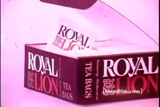 The still features a box of 'Royal Lion' tea bags, prominently displaying the brand name in bold lettering. The packaging is designed with a red and black color scheme, emphasizing its product type. The background has a soft, pinkish hue, giving the image a vintage aesthetic typical of the 1970s. The composition focuses on the tea box, suggesting a promotional or advertising context.