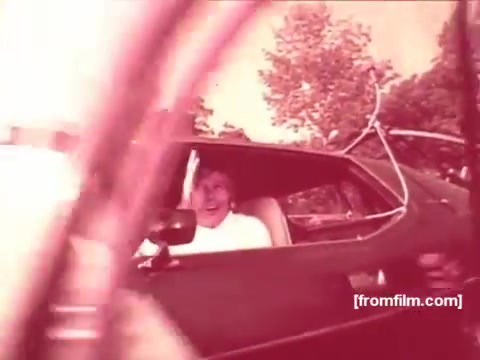 The still captures a scene from a 1970s Pabst Beer commercial, featuring a cheerful individual in a car, waving towards the camera. The image has a nostalgic, vintage aesthetic typical of the era, highlighting outdoor settings with natural light and a friendly vibe. The focus seems to be on promoting an enjoyable, social atmosphere associated with Pabst Beer.