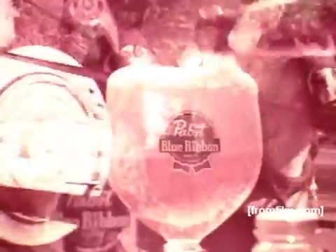The still features a close-up of a large glass of Pabst Blue Ribbon beer, highlighting its frothy top and distinctive logo. The background suggests a lively atmosphere, likely showcasing moments of enjoyment and celebration typical of 1970s beer commercials. The overall tone is nostalgic, reflecting the era's advertising style.