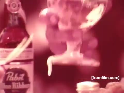 The still likely depicts a hand holding a glass filled with beer, showcasing the drink's frothy head. To the left, a bottle of Pabst Beer is prominently displayed, labeled with its classic design. The color tone appears warm, typical of retro advertising aesthetics from the 1970s, evoking a nostalgic vibe associated with that era's beer commercials.