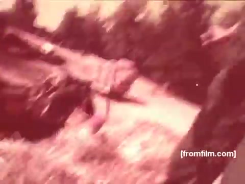 The still from 'Pabst Beer Commercials - 1970's' features a casual outdoor scene, likely depicting moments of leisure. The colors are warm and slightly faded, typical of the 16mm film format from that era. A couple of figures can be seen engaged in activities, suggesting a relaxed, social atmosphere. The overall aesthetic reflects the nostalgic vibe of 1970s advertisements.