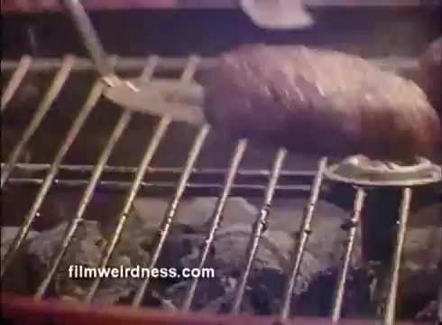 The still showcases a grilling scene, featuring a piece of meat cooking on a grill. The focus is on the meat as it rests on the grill grate, with smoke or heat visible in the background, suggesting a convivial outdoor cooking atmosphere. The overall aesthetic aligns with the celebratory theme of Mardi Gras, likely emphasizing enjoyment and food in relation to the event.