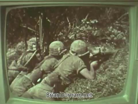The still features a 16mm film frame from a 1960s PSA for the Episcopal Church. It shows soldiers in combat attire, taking cover and aiming their rifles, set against a backdrop of dense foliage. The scene conveys themes of conflict and vigilance, potentially contrasting the military imagery with the church’s messaging about peace or moral responsibility. The visual is presented on a retro television screen, enhancing its vintage quality.