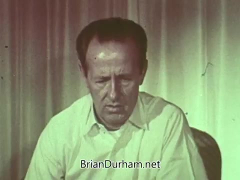 The still features a man with a serious expression, sitting in front of a plain backdrop. He appears to be engaged in a thoughtful or contemplative moment, possibly conveying a message related to the Episcopal Church. The color palette has a muted, vintage quality typical of 1960s film. Overall, the image suggests a focus on personal reflection or a call to action in the context of a public service announcement.