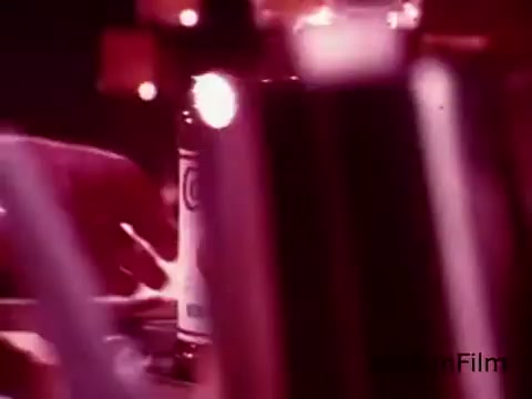 The still from the 16mm print of the 'Coffee-Mate Commercial - Space Needle - 1970's' captures a close-up shot of a hand reaching towards a Coffee-Mate bottle amidst a soft-focus background. The color palette is warm, hinting at a nostalgic and inviting atmosphere typical of 1970s commercials. The use of light and shadow creates an intimate setting, likely focusing on the experience of enjoying coffee with the product. The Space Needle may serve as a backdrop or thematic element emphasizing a connection to Seattle.