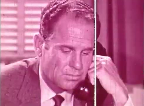 The still features a man looking intently down while holding a telephone receiver to his ear. His expression suggests concentration or concern. The color scheme is predominately pinkish, likely reflecting the aesthetic of the educational film. The background shows a light-colored window blind, indicating an indoor setting. This shot may illustrate a moment of communication or information exchange relevant to the topic of human cells and cytology.