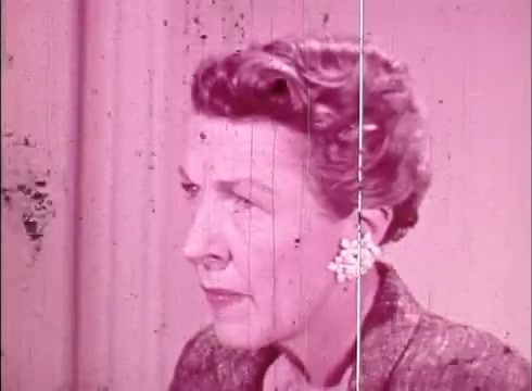 The still features a woman in profile, likely a presenter or educator, engaged in a discussion related to cytology. She has neat, styled hair and wears a formal outfit, complete with a decorative earring. The image has a pinkish hue, indicative of the film's age, with visible wear evident through scratches and lines on the print. The overall composition reflects a mid-20th century educational film aesthetic.