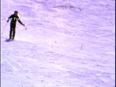 The still depicts a skier making their way down a snow-covered slope. The scene captures a winter landscape with bright, frosty hues, showcasing the enjoyment of physical activity in a snowy environment, in line with the themes of fitness and sports from the PSA featuring John Denver.