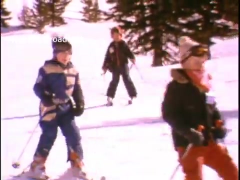 The still features children skiing in a snowy landscape, promoting physical activity and fitness. They are dressed in colorful winter clothing, embodying a joyful spirit. The scene captures a sense of fun and adventure in outdoor sports, aligning with the theme of the PSA by John Denver, which encourages active lifestyles for youth.