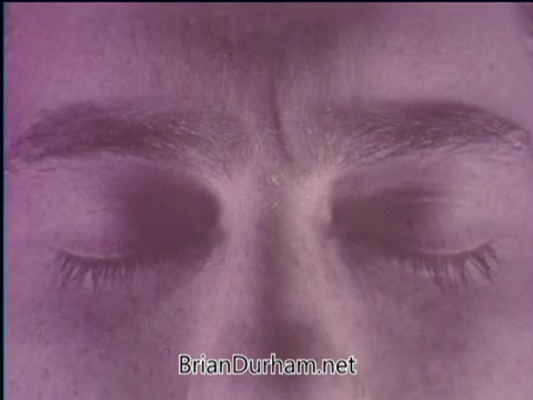 The still features a close-up of a person's face, focusing on their closed eyes and brow. The image has a soft, purple tint, creating a serene and contemplative atmosphere. This visual likely aligns with the themes of faith and health discussed in the PSA, suggesting introspection and mindfulness.