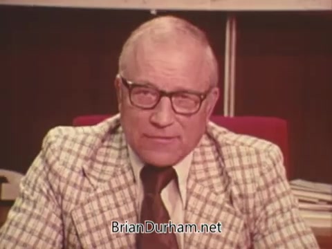 The still features a middle-aged man with glasses, wearing a plaid suit, seated in front of a desk. He appears to be speaking directly to the camera, likely conveying a message related to the campaign against Issue Six in Ohio, which pertains to nuclear power. The setting is formal, emphasizing the seriousness of the political topic.