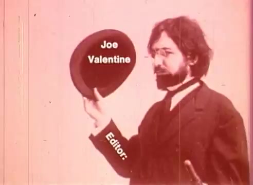 The still features a man in period attire, wearing glasses and a mustache, holding a hat aloft. The image has a vintage quality, typical of a 16mm film, with a soft focus and a slight pink tint. Overlayed text identifies 'Joe Valentine' as the editor, suggesting his role in the production of 'Erik Satie and the King of the Beans - Part II.' The overall aesthetic evokes a whimsical, historical ambiance associated with early cinema.