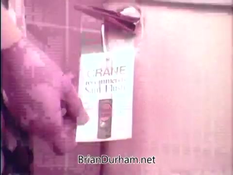 The 16mm still from 'Sani Flush - Wipes out household germs in 15 seconds' features a close-up of a hand holding a product labeled 'Sani Flush.' The image emphasizes the product's effectiveness against household germs, likely set against a bathroom background. The overall tone appears promotional, focusing on cleanliness and hygiene.