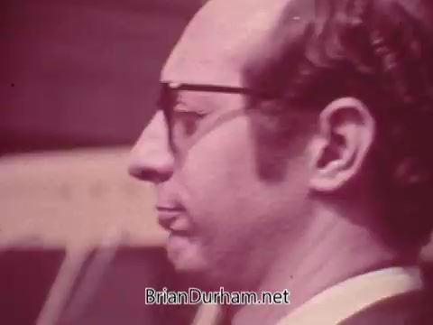 The still features a man with glasses, showcasing a thoughtful expression. He has a distinct profile, and the color tones appear warm and slightly muted. The commercial likely captures a relatable moment tied to the promotion of Iron City Beer, reflecting a casual or humorous sentiment typical of vintage advertisements.