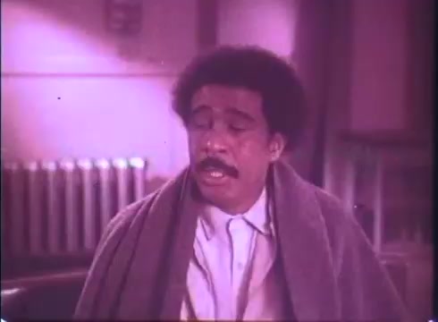 The still from 'Silver Streak' features a man with an afro, dressed in a collared shirt, and wrapped in a blanket. He appears contemplative or distressed, set against a slightly muted, warm-toned background. The scene suggests an emotional moment, typical of the film's blend of comedy and drama. The 16mm print adds a vintage quality, enhancing its nostalgic charm.