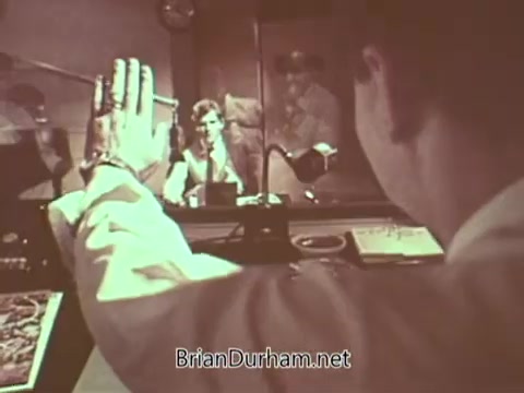 The still from the 'Radio Free Europe PSA' features a radio studio setting where a person is gesturing with their hand, likely signaling to the host or a guest. The focus seems to be on communication, with visual elements suggesting a broadcast scenario. The atmosphere captures the essence of sharing important messages, indicative of Radio Free Europe's mission to provide news and information.