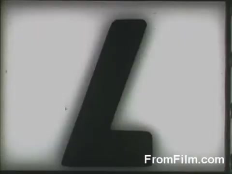 The still features a large, black letter 'L' against a light background, likely serving as a title card or frame indicator from the film. It is connected to the Doolittle Raid, a significant military operation during World War II, where B-25 bombers were launched from the USS Hornet on April 18, 1942. The image may emphasize the operation's historical importance or serve as a cinematic transition.