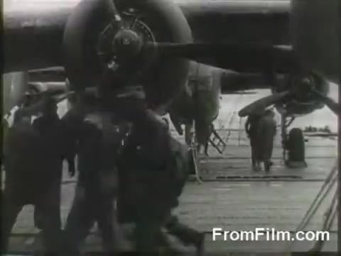 The still captures a pivotal moment during the Doolittle Raid, showing crew members preparing B-25 bombers on the flight deck of the USS Hornet. The scene is bustling with activity as the raiders get ready for takeoff on April 18, 1942, highlighting the intensity and urgency of this historic mission against Japan. The aircraft's engines are prominently featured, emphasizing their readiness for the daring launch.