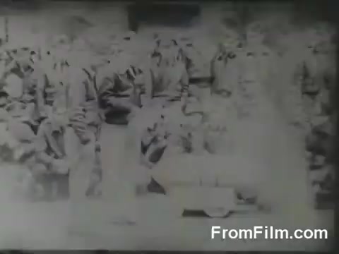 The 16mm still captures a moment from the Doolittle Raid, showing a group of uniformed military personnel on the deck of the USS Hornet. The image appears somewhat faded and unclear, likely due to its age. The soldiers are likely preparing for the launch of their B-25 bombers, embodying the tense and determined atmosphere of this historic military operation on April 18, 1942.
