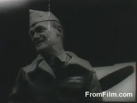 The still features a man in a military uniform and cap, likely a pilot or officer, with a serious expression. The background hints at an aircraft, possibly a B-25 bomber, indicating the context of the Doolittle Raid. The overall tone is historical, capturing a moment before the significant air mission launched from the USS Hornet on April 18, 1942. The image has a vintage quality, common in footage from that era.