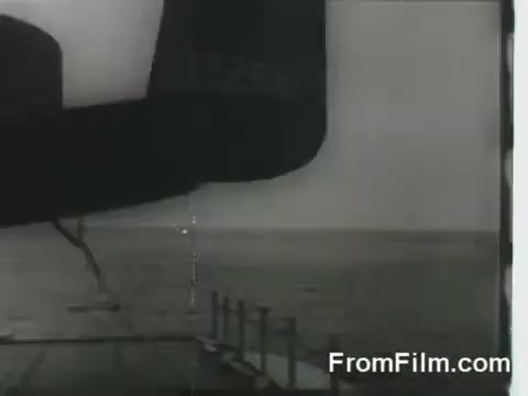 The still shows a B-25 bomber preparing for takeoff from the flight deck of the USS Hornet during the Doolittle Raid on April 18, 1942. The aircraft's silhouette is prominent, with the expansive ocean visible in the background, illustrating the tense and historic moment of the raid's launch.