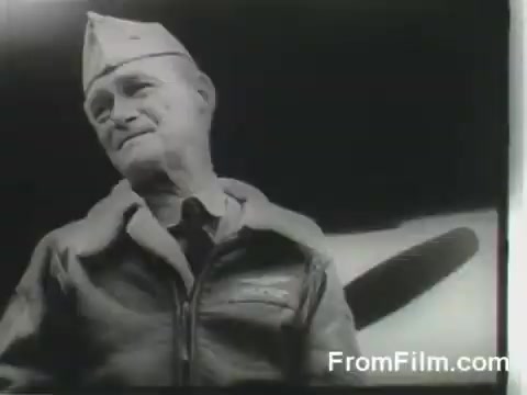 The still captures a moment from the Doolittle Raid, showing a military figure in a bomber jacket and cap, looking proud and resolute. The background hints at an aircraft, likely one of the B-25s used in the mission. This scene embodies the spirit of bravery and determination of the raiders as they prepared for their April 18, 1942, mission from the USS Hornet.