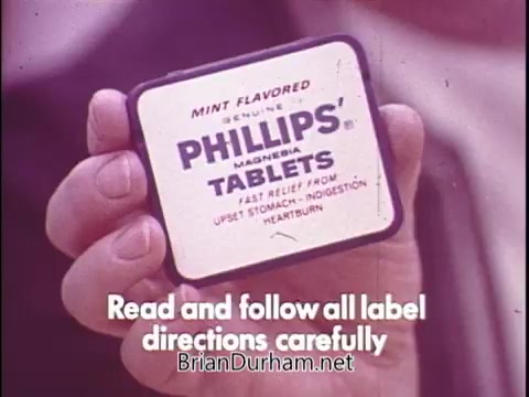 The still features a close-up of a hand holding a package of Phillips Milk of Magnesia tablets, specifically labeled as 'Mint Flavored.' The image emphasizes a clear message in white text at the bottom, urging viewers to 'Read and follow all label directions carefully.'   As for the character you mentioned, Flo from *Alice*, I cannot confirm whether she is in the image or if this still features her.