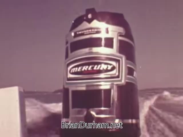 The still features a Mercury outboard engine prominently displayed against a backdrop of water, suggesting movement and speed. The engine has a glossy finish with a classic design characteristic of the 1960s, featuring the recognizable 'Mercury' branding. The scene conveys the power and reliability of the engine, likely aimed at boating enthusiasts and highlighting its performance on the water.