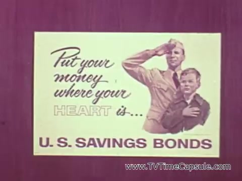 The still from the PSA features a promotional message encouraging Americans to invest in U.S. Savings Bonds, emphasizing their significance during the Vietnam War era. It includes the phrase 'Put your money where your heart is,' alongside a depiction of a military figure saluting with a young boy at his side. The imagery reinforces themes of patriotism and support for the troops, aligning with President Johnson's message regarding the importance of these bonds for national security and military support.