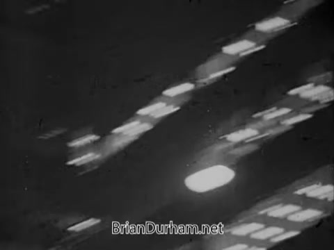 The still from the 1967 PSA by the National Council on Alcoholism features a black-and-white night scene, likely portraying urban lighting effects. The image captures blurred lights, suggesting motion or speed, which may evoke themes of urgency or the chaotic nature of alcoholism's impact. The overall atmosphere appears somber, consistent with the serious subject matter of the PSA.