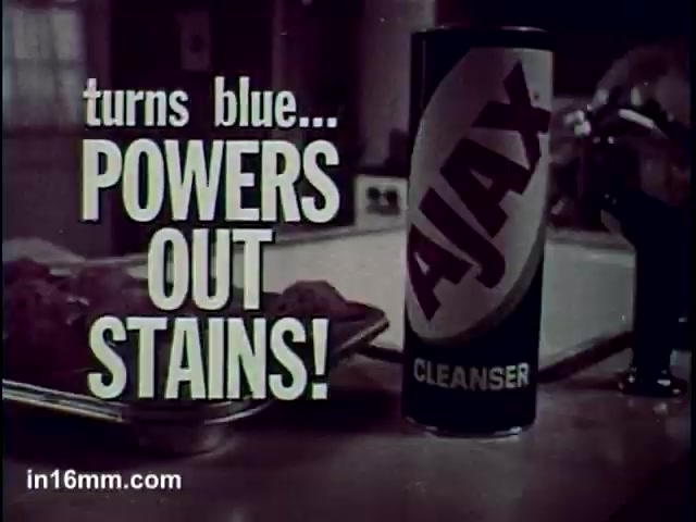 The still features a can of Ajax Cleanser prominently displayed on a countertop. The text emphasizes its effectiveness, stating 'turns blue... POWERS OUT STAINS!' The background suggests a home setting, possibly a kitchen, and the overall tone is focused on promoting the cleaning product's stain-fighting capabilities.