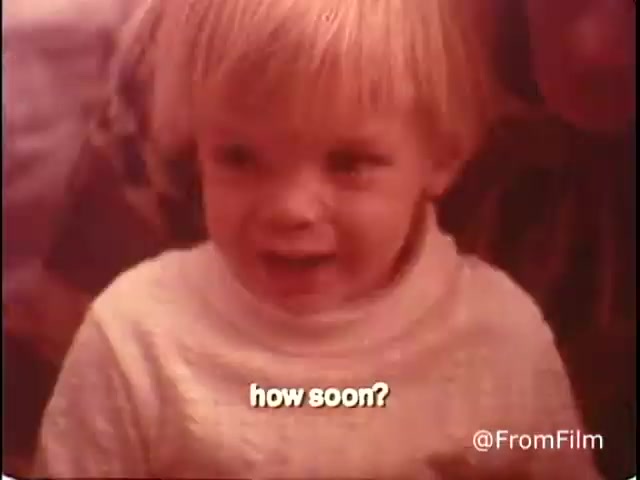 The still from the 16mm film 'Closer Look - 1970's PSA Parents' Campaign for Handicapped Children and Youth' features a young child with blond hair, expressing curiosity or eagerness with the question 'how soon?' The background appears warm-toned, hinting at a positive and engaging atmosphere, typical of public service announcement films from that era. The image highlights themes of childhood innocence and anticipation.