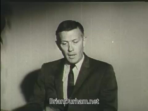 The still features a man in a suit, seated and speaking directly to the camera. He appears engaged and serious, likely discussing heart health or raising awareness for the American Heart Association. The background is simple and subdued, emphasizing his message.