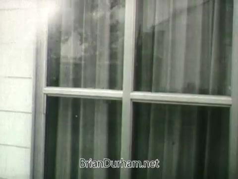The still from the 1960s Public Health Service Clean Air PSA features a close-up of a window with curtains drawn. The window frame is metallic, and the scene likely emphasizes domestic life and air quality. The muted tones and vintage aesthetic reflect the era's cinematic style, supporting the PSA's message about the importance of clean air in homes.