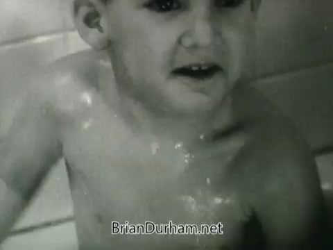 The still is from a Public Health Service PSA focused on clean air, likely from the 1960s. It features a young child, appearing soap-covered and possibly bathing, conveying a message about health and cleanliness. The black-and-white image suggests a nostalgic tone, highlighting childhood innocence in relation to public health themes.