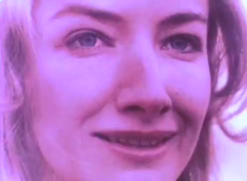 The still features a close-up of a woman with light blonde hair and blue eyes. Her expression is earnest, suggesting a sense of vulnerability or sincerity. The colors appear muted, with a soft, possibly nostalgic quality typical of a 16mm print. This image likely aims to evoke empathy and encourage viewers to reconsider their perceptions of ex-offenders.