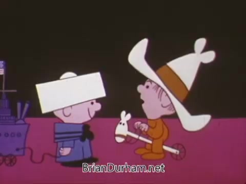 The still features two animated characters in a colorful setting. One character, dressed in a navy uniform with a white hat, stands next to a toy ship. The other character, wearing an oversized cowboy hat, rides a toy horse. The scene suggests a playful interaction, likely aimed at promoting Navy recruiting in a lighthearted manner.