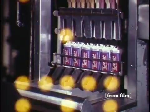 The still from 'Making Frozen Novelties - 1967 Kodachrome' showcases a segment of industrial footage focused on the production of ice cream novelties. In the frame, you can see a machine dispensing and packaging colorful popsicle-like treats, likely featuring a variety of flavors. The setup appears to be efficient, indicating an assembly line process typical of food manufacturing in the late 1960s. The vibrant colors characteristic of Kodachrome film enhance the nostalgic feel, making it a glimpse into the past of food production. This footage serves as a valuable historical insight into the ice cream industry of that era.